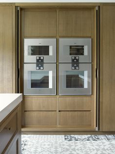 two double ovens in the middle of a kitchen with wood cabinets and tile flooring