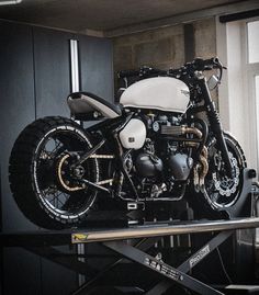 a black and white motorcycle parked on top of a metal stand in front of a window