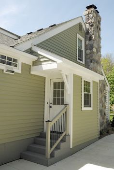 a house with a stone chimney and white trim