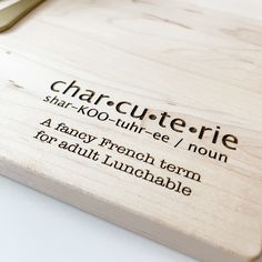 a wooden cutting board with the words charcuterie written on it and a knife next to it