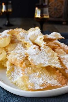 a white plate topped with dessert covered in powdered sugar on top of a blue table cloth