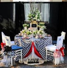 a table set up with black and white checkered cloths, red bows, and flowers