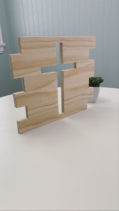 a cross made out of wood sitting on top of a table next to a potted plant