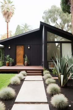 a black house with some plants in the front yard