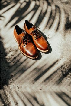 a pair of brown shoes sitting on top of a sandy beach