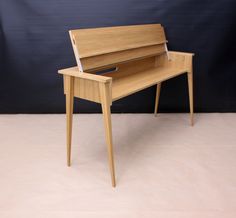 a wooden desk sitting on top of a white floor next to a blue wall and black backdrop