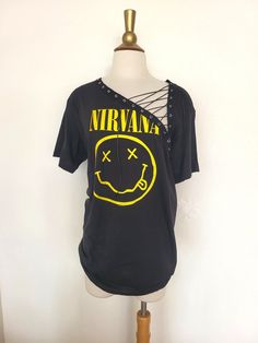 "Nirvana Lace Up Band Top T Shirt - Grunge - Smiley Face Nevermind Each piece is uniquely designed and one of its' kind. Hand stitched edge detailing for superior quality and unique finish. Please note, since this is a handmade item, there may be slight variances with each T.  UNISEX Sizing (women may choose to size down depending on fit preference) Appx. Measurements Laying Flat: S: 17\" across chest Width x 28\" Length M: 19\" across chest Width x 29\" Length L: 21\" across chest Width x 31\" Length ** If you have a custom idea or would like to mix and match a design idea seen in my shop, feel free to contact me anytime **" Edgy Festival T-shirt With Crew Neck, Vintage Distressed T-shirt For Festivals, Edgy Screen Print Tops For Music Festivals, Punk Style Summer Festival T-shirt, Distressed Punk T-shirt, Edgy Acid Wash T-shirt For Alternative Fashion, Grunge Screen Print Tops For Music Festival, Grunge Festival Top With Screen Print, Grunge Screen Print Top For Festival