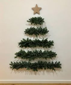 a christmas tree made out of pine branches with a star hanging on the wall behind it