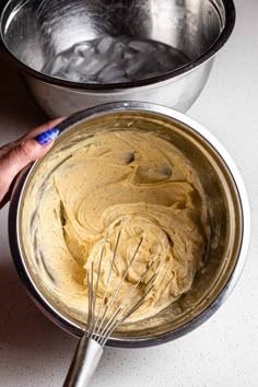 a person whisking batter into a metal bowl