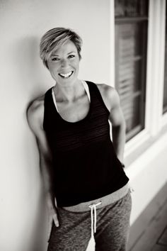 a black and white photo of a woman leaning against a wall with her mouth open