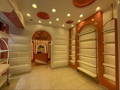 the interior of a store with white shelves and orange accents on the walls, along with an arched doorway that leads to another room