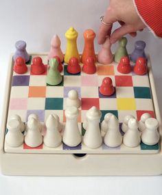 a person is playing chess on a checkered board with white and red pawns