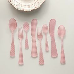 pink polka dot plastic utensils and spoons on a white tablecloth next to a plate