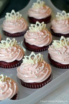 cupcakes with pink frosting and white icing in a plastic tray on a table