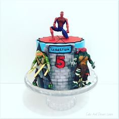 a spiderman birthday cake with five figurines on top and the number 5