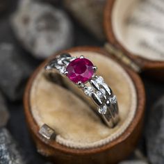 This stunning ring is centered with one (1) oval mixed cut natural ruby weighing 1.05 carats and set into a four-prong head. The shoulders of the ring are each accented with five (5), channel set, round brilliant cut diamonds. The ring measures 6.2mm at the top, rises 5.1mm above the finger, tapering to 2.6mm wide and 1.7mm thick at the base of the shank. This ring is currently a size 6.25. Timeless Round Cut Ruby Diamond Ring, Timeless Ruby Ring With Round Cut Center Stone, Ruby Diamond Ring With Accent Stones And Round Cut, Ruby Ring With Accent Stones In Platinum, Timeless Ruby Ring With Center Stone, Platinum Ruby Ring With Accent Stones, Ruby Wedding Ring With Round Cut And Accent Stones, Ruby Ring With Accent Stones Round Band, Fine Jewelry Ruby Ring With Accent Stones In Platinum