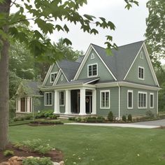 a green house with white trim on the front and side windows is surrounded by trees