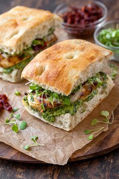 two sandwiches sitting on top of a wooden cutting board