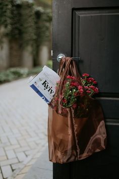 a brown paper bag with flowers hanging from it's side on a black door