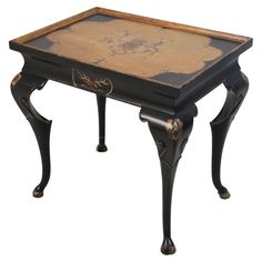 an old black and gold side table with flowers painted on the top, sitting against a white background