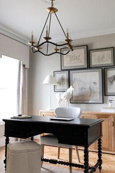 a black desk and chair in a room with pictures on the wall above it, along with a lamp