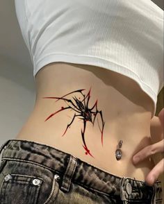 a woman's stomach with a spider tattoo on the side and red paint splatters all over it