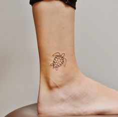 a woman's foot with a small turtle tattoo on the side of her ankle