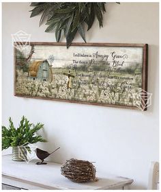 a painting hanging on the wall above a table with plants and a potted plant