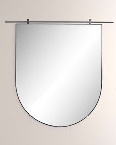 a mirror hanging on the wall with a metal bar around it's edge and an oval shaped frame