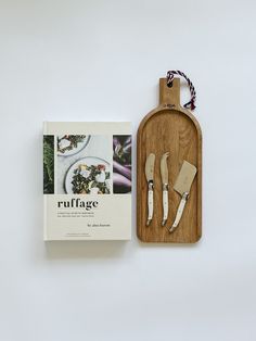 a wooden cutting board with utensils in it and a book on the side