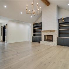 an empty living room with fireplace and built in bookshelves