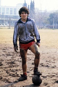 a young man standing on top of a dirty soccer ball