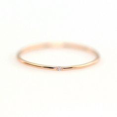 a gold ring with a single diamond on the top and bottom, sitting on a white surface