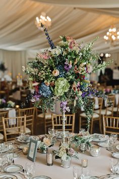 an image of a table setting with flowers in vases and candles on the tables