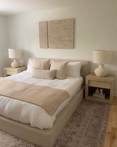 a large bed sitting in the middle of a bedroom next to two nightstands with lamps on each side