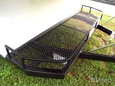 a metal bench sitting on top of green grass next to a white wall and floor