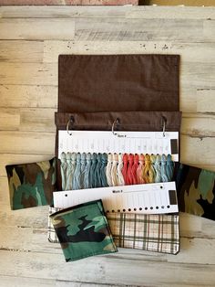 an assortment of fabric samples are displayed on a wooden surface, along with a notepad and pen holder