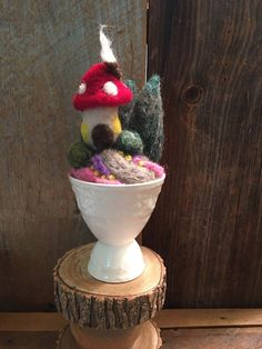 a white bowl filled with knitted items on top of a wooden stand