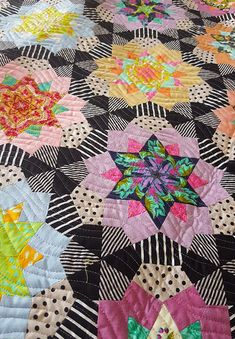 a close up of a quilt with many different colored flowers on the top and bottom