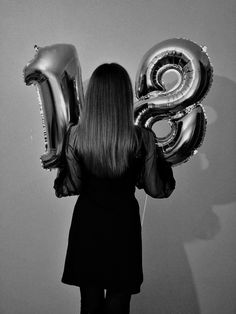 a woman standing in front of balloons with the letter b on it's back