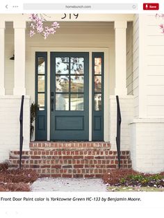 the front door is painted blue and has pink flowers in blooming on the steps