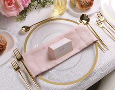 a table set with plates, silverware and pink napkins for an elegant dinner