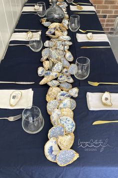 a long table is set with blue and white plates, silverware, and napkins