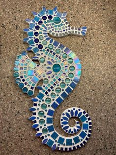 a seahorse made out of glass sitting on the side of a wall next to a tile floor