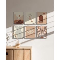 a set of four abstract paintings hanging on a wall next to a wooden cabinet and sideboard