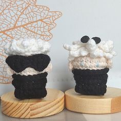 two knitted cupcakes sitting on top of wooden bases