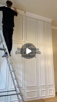 a man standing on top of a ladder next to a white closet and holding onto the wall