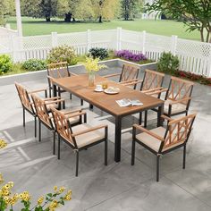 an outdoor dining table and chairs set up on a patio with flowers in the background