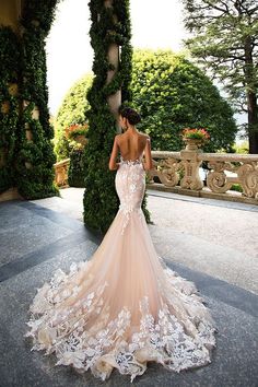 a woman in a wedding dress is looking at the back of her gown, which has flowers on it