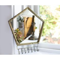 a mirror hanging on the side of a window sill next to a potted plant